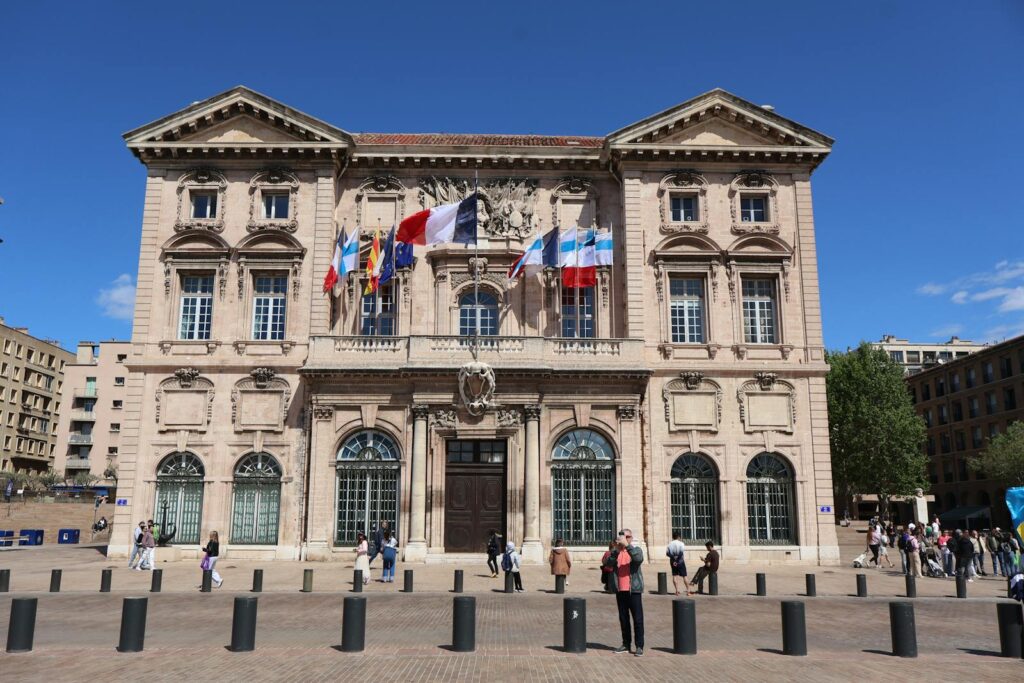 Capture of iconic Marseille City Hall with flags, showcasing classic architectural elegance.